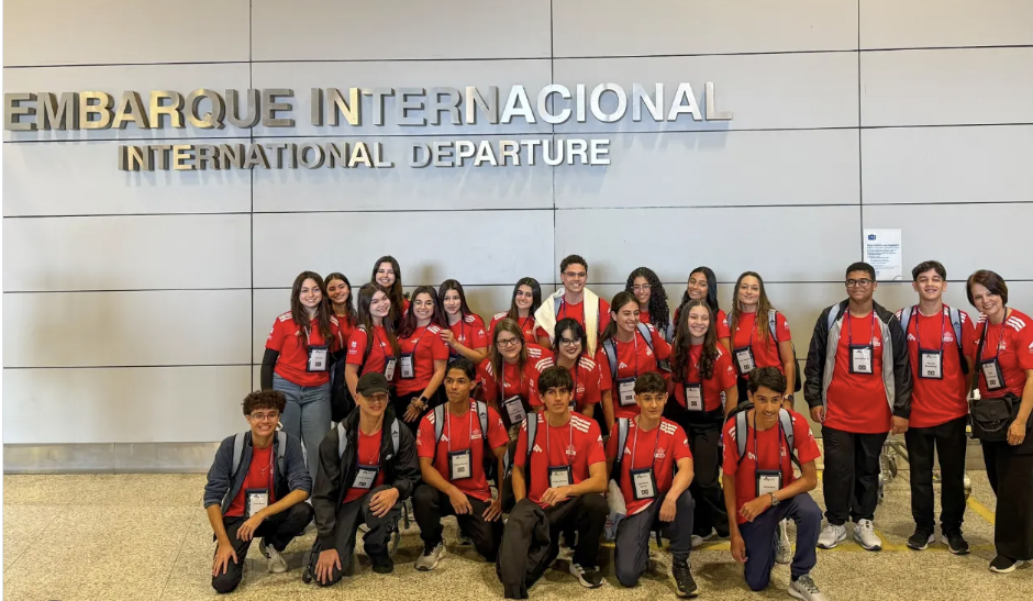 Grupo de alunos com camisas vermelhas no embarque internacional do aeroporto